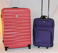 Two suitcases standing side by side, red hard shell and purple soft shell with extended handles visible.