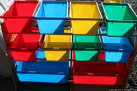 Front view of colorful kids bin holder with three rows of 4 smaller bins and bottom shelf with 4 larger bins in red, blue, yellow, green.