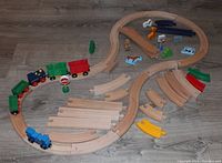 Full view of assembled wooden railway train set with train and accessories on floor.