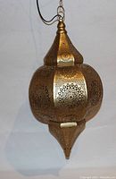 Close-up of the Moroccan style light showing detailed perforated metalwork and bulbous shape with pointed bottom finial.