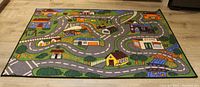 Top-down image of the colorful children's play rug showing roads, buildings, and landscape details.