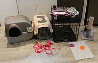 Overall view of pet accessories including carriers, collapsible cage with pet clothes on top, harnesses, feeding mats and cat scratch post.