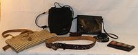 Lot containing two purses, one wallet, and three belts arranged on a flat surface.