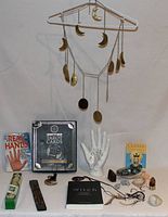 Front view of the lot showing boxed tarot cards set, palmistry hand model, books, crystals, incense, and hanging brass moon mobile.