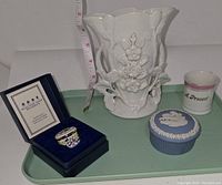 Front view of porcelain spill vase, Wedgwood pillbox, vintage pillbox in blue box, and small porcelain cup on green tray with measuring tape