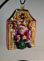 Front view of the Christopher Radko glass Christmas ornament depicting Santa Claus in a fireplace with stockings and colorful details.