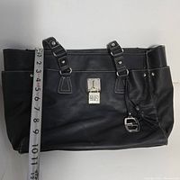 Front view of the Ellen Tracy black faux leather tote bag showing lock charm, straps, and stitching