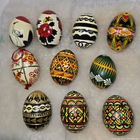 Top and front view of 10 hand painted decorative eggs showcasing various detailed folk art designs in bold color schemes.