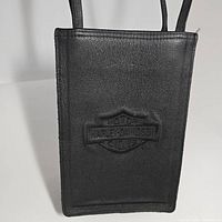 Full front view of black leather Harley Davidson tote showing embossed logo and two handles.