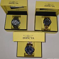 Group shot of three Invicta watches in original yellow Invicta boxes