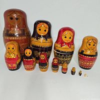 Photo showing all 13 nesting dolls arranged in a row from largest to smallest, displaying the design details and size progression.