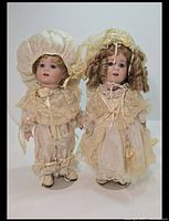 Two SFBJ 247 New Orleans twin porcelain dolls standing side by side showing full outfits and facial details.