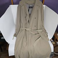 Front view of beige double-breasted Newport trenchcoat with belt laid flat showing full length.