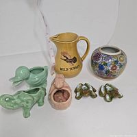 Display of all six pottery items including animal-shaped planters and a pitcher beside a floral bowl