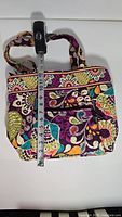 Front view of the Vera Bradley Plum Crazy quilted tote bag with measuring tape showing approximate 9.5 inch height.