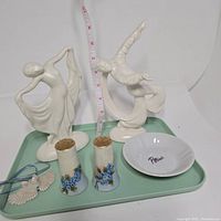 Full view of the lot showing the two white ceramic Art Deco dancing figurines, floral salt and pepper shakers, owl pendant necklace, and Perino's white dish on a mint green tray.