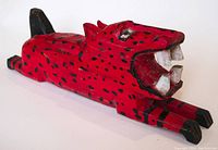 Front side view of the red painted wooden leopard folk art carving with mouth open showing teeth and black spots.