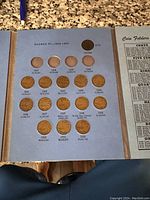 Inside view of coin folder showing Canadian pennies from George VI era with some coins missing