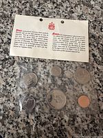 1974 Canadian coin set laid out on granite surface with certificate card, front showing English text and Canadian coat of arms logo.