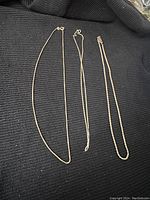 Three 925 silver chains on black fabric background showing different chain styles and clasps.