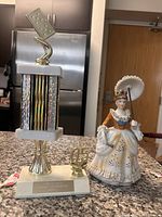 Overall view of the domino tournament MVP trophy and porcelain lady figurine on counter