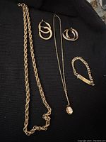 Top view showing all jewelry pieces arranged on black cloth including necklaces, bracelet and earrings