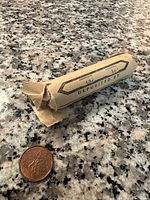 Photo of a wrapped roll of pennies on a speckled granite surface alongside a single penny coin.