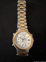 Front view of the Seiko watch showing white dial with chronograph subdials, gold bezel, and two-tone metal band.