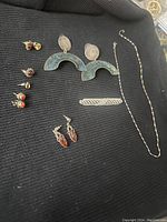 Photo of all jewelry laid out on black fabric showing earrings, necklace, and pin