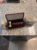 Silver elephant figurine, Miray cocktail jigger in presentation box, and ceramic pot on granite countertop.