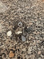 Photo of sterling silver charm bracelet showing various detailed charms and linked chain structure on a speckled surface.