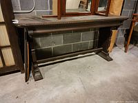 Front and side views of the antique wooden writing table showing carved edge detail, fluted legs, gate style leg construction with central stretcher, and surface finish condition.