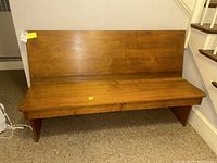 Front view of wooden bench showing polished medium-tone wood finish and flat seating.