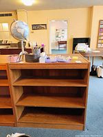 Two matching wood bookcases shown with three shelves each, medium brown finish, scratches and chips on back panels visible.