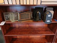 Full view of all five bookends including glass, wooden and plastic ones on a wooden shelf.