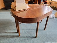 Two wooden console tables with rounded rectangular tops and four cylindrical legs. The tables have visible surface scratches and a warm wood finish.
