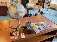 Photo showing the table top globe and various desk supplies arranged on a wooden table.