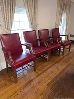 Four matching red upholstered armchairs in a row against wall and window