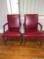 Front view of two matching red armchairs showing upholstery and frame
