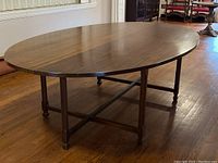 Full view of oval wooden table with cross-stretcher base