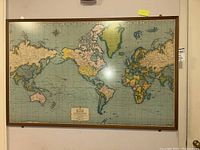 Front view of the entire framed map showing continents and oceans with a decorative cartouche at the bottom center.