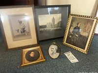 Group photo of five framed portraits and a church picture leaning against a wall on a carpeted floor