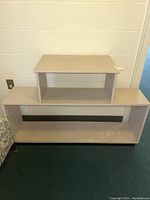 Front view of the wooden shelving unit showing stepped two-level design with one small top shelf and larger bottom shelf.