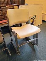 Front-facing view of stacked chairs showing white seats and chrome frames