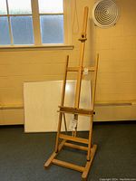 Wooden Windsor & Newton Shannon Studio Easel standing on floor near window with attached guarantee tag visible