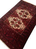 Top angled full view of the Baluchi Persian rug showing colors and central medallion pattern.