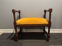 Front view of antique French carved wooden bench stool with yellow upholstered seat