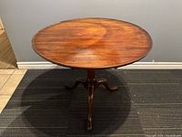 Front view showing round mahogany tabletop and tripod base.