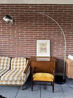 Full view of arc lamp behind sofa against brick wall showing entire lamp structure, shade and base