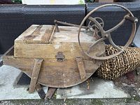 Side angle showing wooden frame, crank handle, and overall shape of antique washing machine.